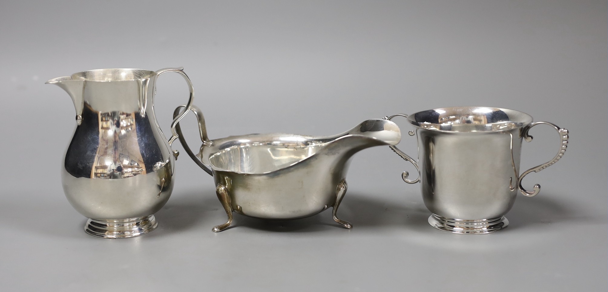 A small silver jug, Birmingham 1946 by Thomas Ducrow & Sons, together with a silver two handled cup, London 1973 by Tessiers Ltd and a silver sauceboat, 12oz.
